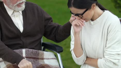 Hija-llorando-cerca-de-viejo-padre-en-silla-de-ruedas,-presionado-con-noticias-sobre-el-cáncer