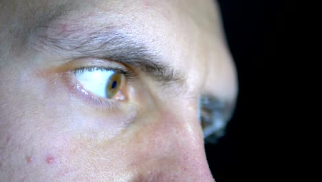 Close-up-of-the-eyes-and-face-of-a-young-man-working-at-a-computer-on-a-Black-Background