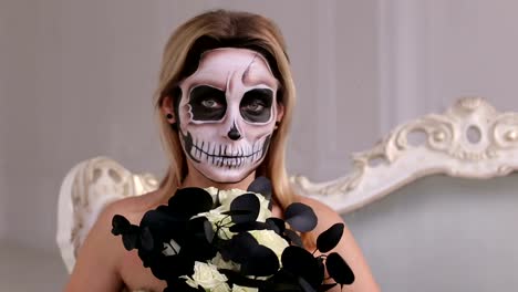 Mädchen-in-einem-Kleid-mit-einem-Blumenstrauß-und-Make-up-in-Form-eines-Skeletts