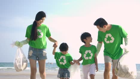 Group-of-volunteers-in-green-t-shirts-cleaning-up-the-beach-with-plastic-bags-full-of-garbage.-Slow-Motion.-Safe-ecology-concept.-4k-resolution.