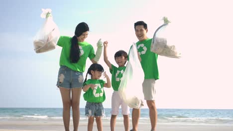 Group-of-volunteers-in-green-t-shirts-cleaning-up-the-beach-with-plastic-bags-full-of-garbage.-Slow-Motion.-Safe-ecology-concept.-4k-resolution.