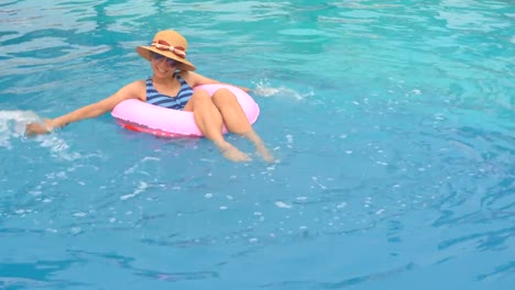 Chica-jugando-y-nadando-en-el-anillo-de-goma-flotando-en-la-piscina