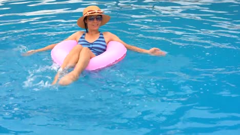 Chica-jugando-y-nadando-en-el-anillo-de-goma-flotando-en-la-piscina