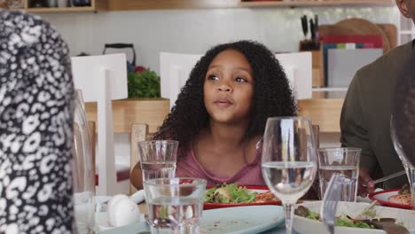 Family-Sitting-Around-Table-At-Home-Enjoying-Meal-Together