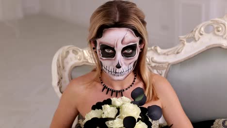 Porträt-der-Frau-mit-schrecklichen-Halloween-Skelett-Make-up-sitzt-auf-einem-Sofa.