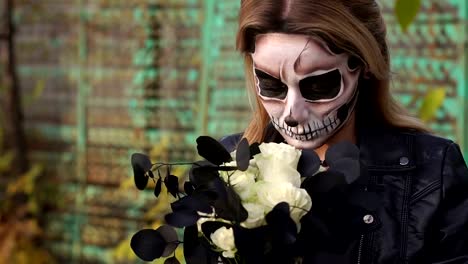 Creepy-bride-with-a-bouquet-of-black-flowers-and-make-up-in-the-form-of-a-skull.