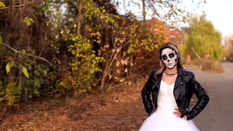 A-young-girl-with-a-creepy-make-up-in-the-form-of-a-skull-on-a-empty-road.