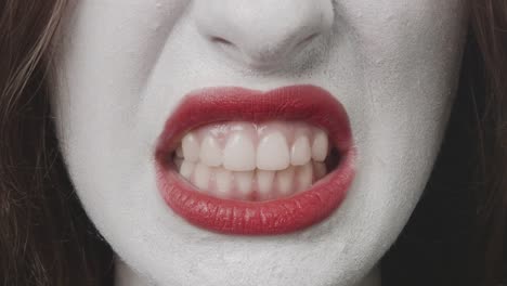 Baring-the-teeth---close-up-of-a-teenage-girl,-who-is-made-up-for-Halloween-or-a-costume-party.-Rehearsing-different-facial-expressions,-she-is-baring-her-teeth