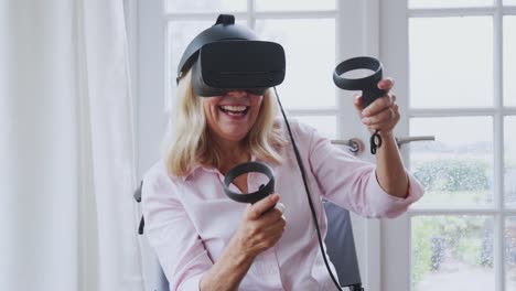 Mujer-discapacitada-madura-en-silla-de-ruedas-en-casa-usando-auriculares-de-realidad-virtual-que-sostienen-los-controladores