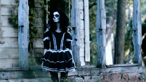 Halloween.-A-woman-dressed-in-black-clothes-standing-in-front-of-wooden-house.-4K