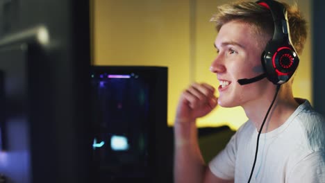 Aufgeregt-Teenage-Boy-tragen-Headset-gewinnen-bei-Gaming-zu-Hause-mit-Dual-Computer-Bildschirme