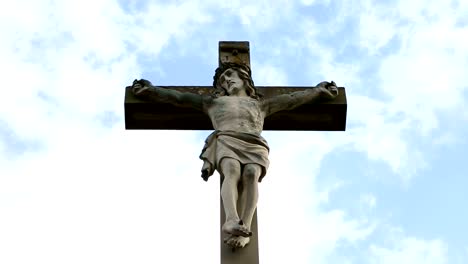 Nahaufnahme-des-steinernen-Kreuz-mit-Jesus-und-blauer-Himmel-mit-Wolken