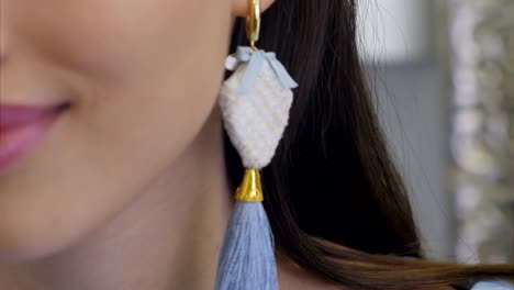 Smiling-elegant-young-woman-wearing-long-earrings-looking-into-mirror-and-smiling