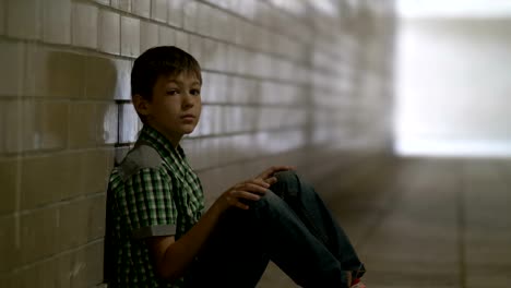 sad-lonely-battered-boy-sits-on-the-floor-in-a-tunnel-in-deep-depression-looking-down,-no-one-is-waiting-for-the-boy-at-home