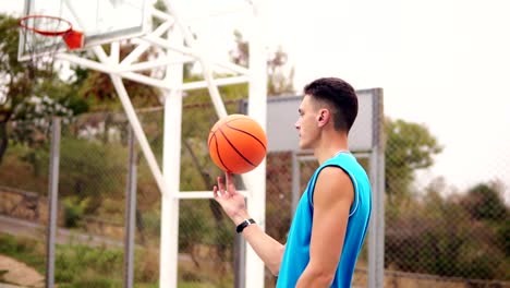 Retrato-de-un-jugador-de-baloncesto-que-hace-girar-una-pelota-de-baloncesto-en-el-patio-de-la-calle.-Tiro-de-cámara-lenta