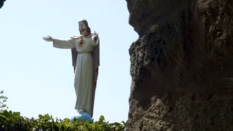 Estatua-de-Jesucristo-contra-el-cielo-azul-en-la-abertura-entre-las-rocas,-vista-panorámica