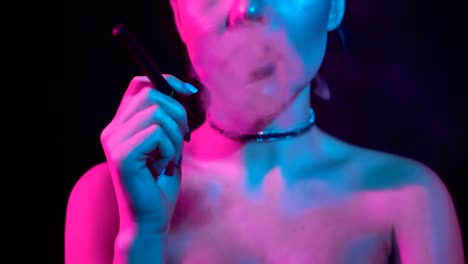 Gorgeous-brunette-woman-smoking-electronic-cigarette-in-neon-color-light