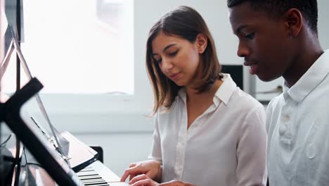 Männliche-Schüler-mit-Lehrer-im-Musikunterricht-Klavier-zu-spielen