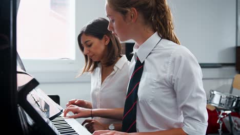 Weibliche-Schüler-mit-Lehrer-im-Musikunterricht-Klavier-zu-spielen