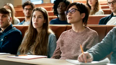 Im-Klassenzimmer-stellt-Smart-asiatische-Studentin-Professor-eine-Frage.-Multi-ethnischen-Gruppe-von-modernen-hellen-Studenten-an-der-Hochschule.