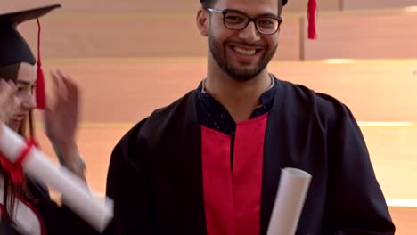 Students-wearing-graduation-gown-talking-and-joking.