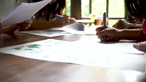 Close-up-of-Young-Asian-students-writing-and-preparing-their-presentation-papers-on-the-table-at-library