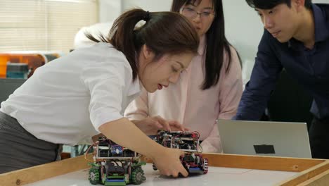 Team-of-robotics-engineer-works-with-robot,-assembling-and-testing-robotics-responses-with-laptop-Computer-in-workshop.-People-with-technology-or-innovation-concept.