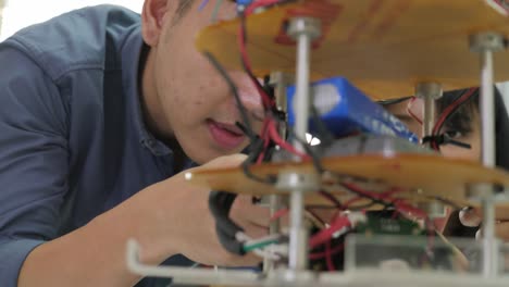Asian-young-electronics-engineer-building-&-fixing-robotics-in-laboratory.-People-with-technology-or-innovation-concept.