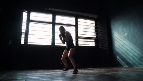 silueta-de-joven-hermosa-mujer-boxeo-entrenamiento-en-gimnasio-de-perforación