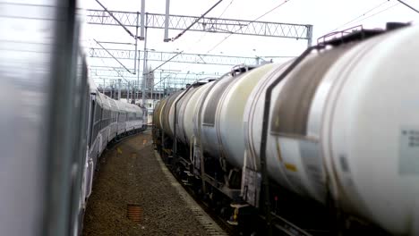 Passanger-train-moving-next-to-cisterns-on-railway-track-in-4k-slow-motion-60fps