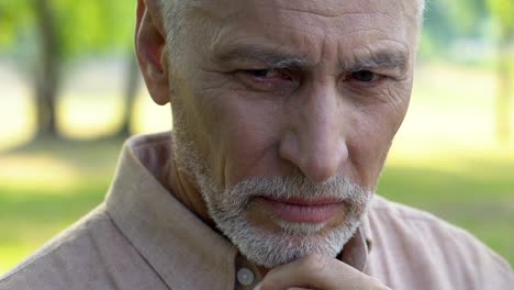 Lonely-old-man-sitting-in-park-and-bitterly-crying,-closing-face-with-hands