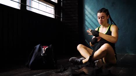 panorámica-ajuste-mujer-envoltura-de-manos-con-cinta-de-vendaje-preparación-de-boxeo-formación-lenta