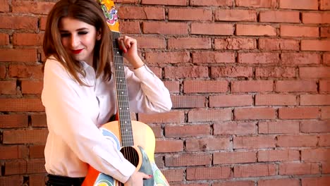 Girl-in-white-shirt-posing-with-a-guitar-in-hippie-style.