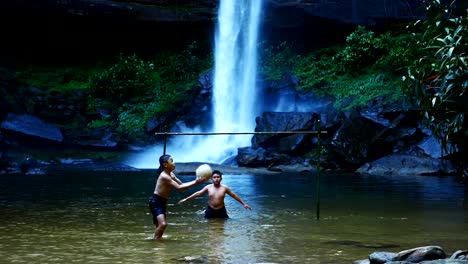 Ländliche-Kinder-schießt-einen-Fußball-am-Wasserfall.-(Zeitlupe)