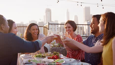 Freunde-versammelt-auf-Dachterrasse-für-Essen-mit-Skyline-der-Stadt-im-Hintergrund