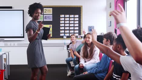 Line-Of-High-School-Pupils-Raising-Hands-To-Answer-Question-Asked-By-Teacher-In-ICT-Class