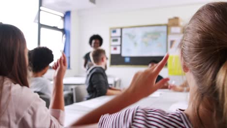 Mujer-alta-Tutor-pidiendo-alumnos-sentados-a-la-mesa-la-pregunta-a-los-que-levantan-sus-manos