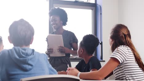 Weibliche-Tutor-Fragen-Gymnasiasten-herumsitzen-Tabelle-Frage,-welche-sie-heben-ihre-Hände