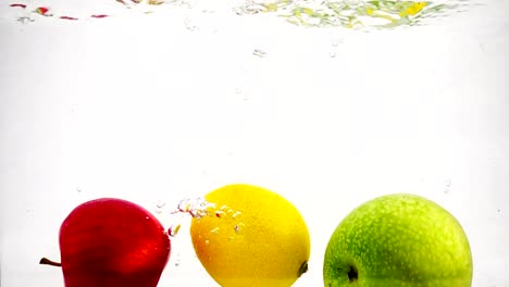 Apfel,-Zitrone-und-Orange-mit-Luftblasen-in-Zeitlupe-ins-Wasser-fallen.-Früchte-auf-isoliert-einen-weißen-Hintergrund.