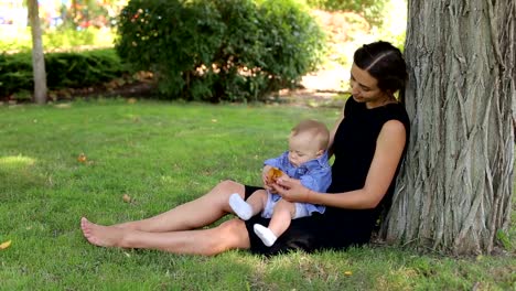 Eine-junge-glückliche-Mutter-geht-mit-ihrem-neugeborenen-Sohn-im-Park-im-Sommer.