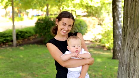 A-young-happy-mother-walks-with-her-newborn-son-in-the-park-in-the-summer.