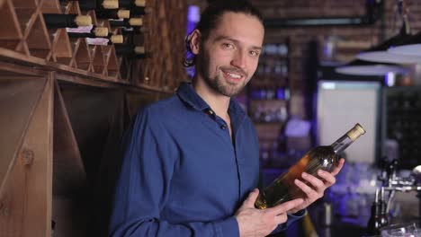 Handsome-Man-Holding-Bottle-Of-Wine-At-Wine-Cellar