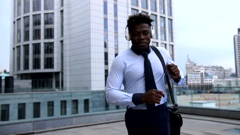 Positive-businessman-with-headphones-dancing-outdoors