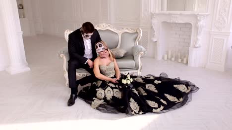 Couple-with-a-creepy-Halloween-makeup-sit-on-a-vintage-sofa-in-a-vintage-room.