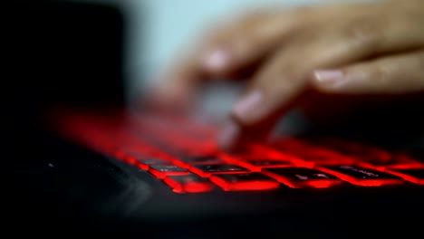 Teenage-Hacker-Girl-greift-Unternehmensserver-in-Dunkelheit-an,-tippen-auf-Red-Lit-Laptop-Keyboard.-Raum-ist-dunkel