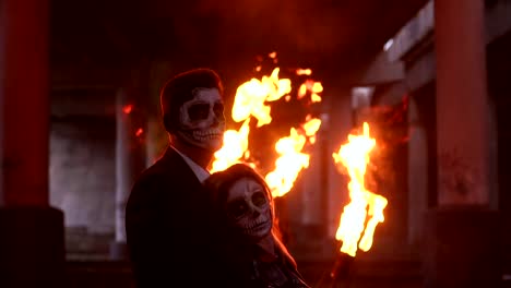 Couple-with-a-terrible-makeup-for-Halloween,-in-the-background-a-huge-flame.