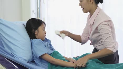 Asiatische-Mutter-reiben-den-Körper-Patient-kleines-Mädchen-für-die-Temperatur-und-körperliche-Untersuchung-im-Krankenhaus-zu-reduzieren.-Konzept-der-Familie,-Medizin,-Gesundheitswesen-und-Technologie.