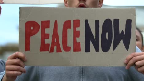 Protesters-with-banners-shouting-Peace-now,-anti-war-movement,-against-terrorism