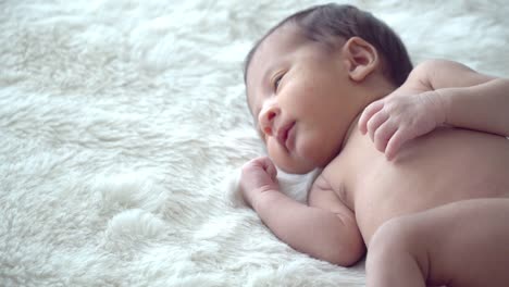 4K-Medium-shot-of-relaxing-adorable-little-asian-newborn-baby-boy-son-sleeping-on-white-bed-in-home-bedroom.-Cute-innocent-newborn-baby-health-care-and-sensitive-skin-concept.