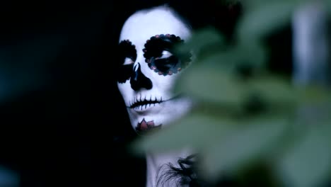 A-young-woman-with-halloween-make-up-holding-a-pumpkin-with-a-lighted-candle.-4K